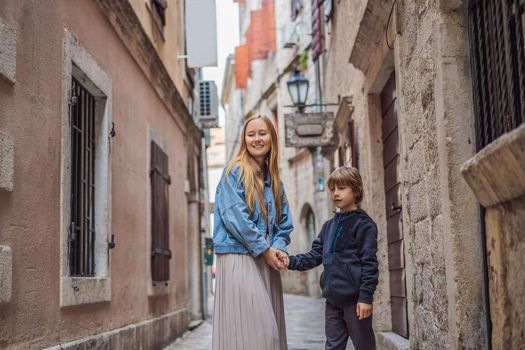 Mom and son travelers enjoying Colorful street in Old town of Kotor on a sunny day, Montenegro. Travel to Montenegro concept.