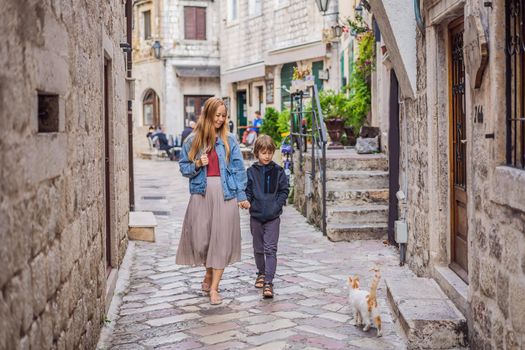 Mom and son travelers enjoying Colorful street in Old town of Kotor on a sunny day, Montenegro. Travel to Montenegro concept.