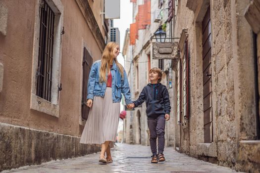 Mom and son travelers enjoying Colorful street in Old town of Kotor on a sunny day, Montenegro. Travel to Montenegro concept.