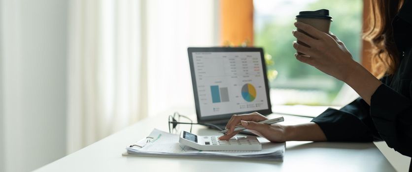 Close up hand of woman planning budget, using calculator, reading documents, young female checking finances, counting bills or taxes, online banking services, sitting at desk.