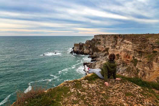 A woman enjoys a beautiful sea view from the top of a cliff.