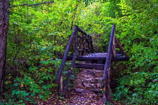 Beautiful wooden handmade bridge in the footpath forest