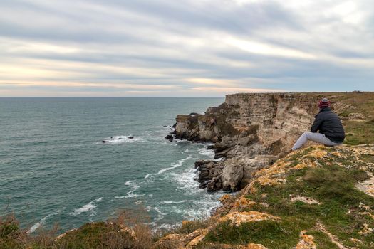 A man enjoys a beautiful sea view from the top of a cliff.