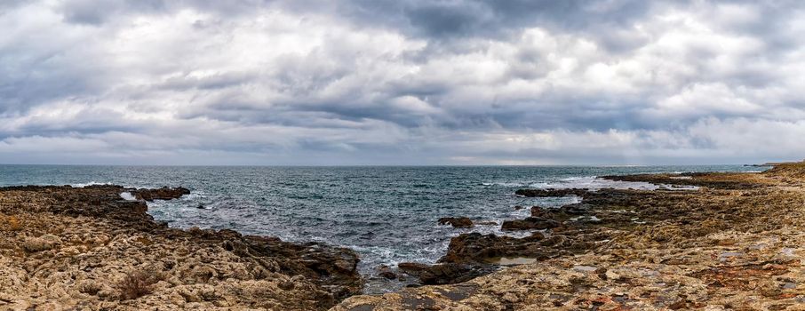 Stunning panoramic seascape with scenic clouds over the sea with rocky shore