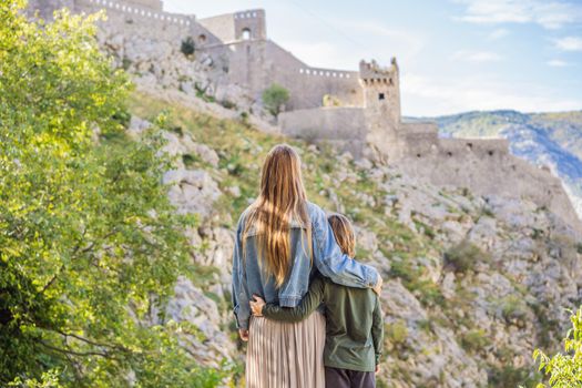 Mother and son travellers enjoys the view of Kotor. Montenegro. Bay of Kotor, Gulf of Kotor, Boka Kotorska and walled old city. Travel with kids to Montenegro concept. Fortifications of Kotor is on UNESCO World Heritage List since 1979.