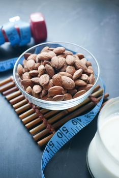 Diet plan with almond nut, dumbbells, milk on table .