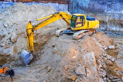 Big yellow excavator working at the construction site.