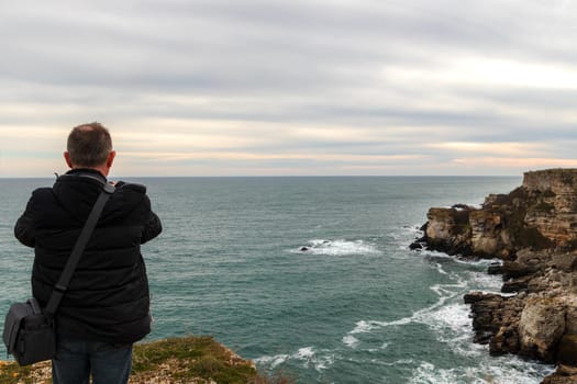 A man make a photo of a beautiful coastline view from the top of a cliff.