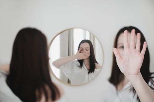 young woman looking in the mirror. Mental health problems in self-isolation at home. Reflection in mirror. Depression, anxiety, phobia, suicide and mental health concept.