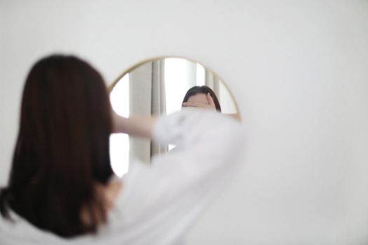young woman looking in the mirror. Mental health problems in self-isolation at home. Reflection in mirror. Depression, anxiety, phobia, suicide and mental health concept.