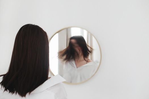 young woman looking in the mirror. Mental health problems in self-isolation at home. Reflection in mirror. Depression, anxiety, phobia, suicide and mental health concept.