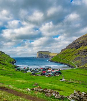 Risin and Kellingin, The Giant and the Wich far in the distance with Tjornuvik village in the foreground under the clouds