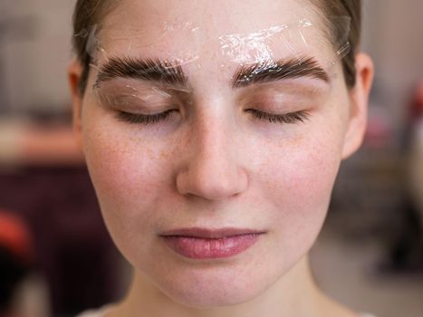 Caucasian woman on the procedure of permanent styling and coloring of eyebrows