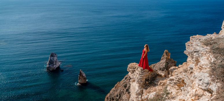 A woman in a red flying dress fluttering in the wind, against the backdrop of the sea