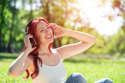 Young attractive woman listens to music in the park. Enjoying music in the park