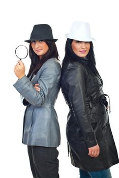 Two beautiful detectives women standing back to back and wearing hats and leather jackets  isolated on white background