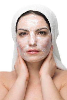Woman  at spa with a white towel on head  and cream facial mask isolated on white background
