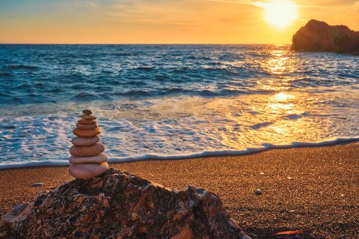 Concept of balance and harmony. Cairn stack of stones pebbles cairn on the beach coast of the sea in the nature on sunset. Meditative art of stone stacking