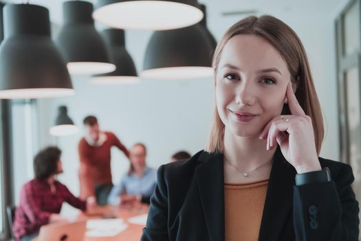Portrait of happy businesswoman owner in modern office. Businesswoman smiling and looking at camera. Busy diverse team working in the background. Leadership concept. Head shot. High-quality photo