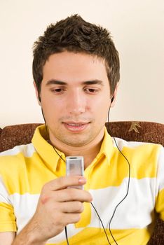 Young happy man listening music on mp3 player in his sofa home