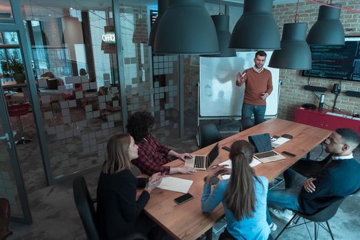 Leader give a business presentation at an office conference meeting, businessman coach mentor explains graph chart on board corporate group workshop training in the boardroom. Selective focus. High-quality photo