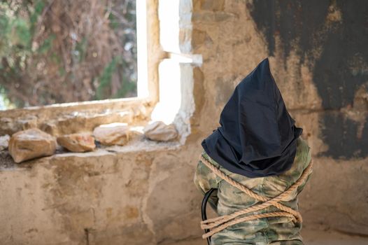 Caucasian woman is taken hostage tied with a rope and with a black bag on her head