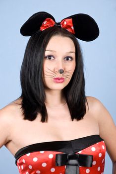 Sexy woman with mouse ears and makeup posing  in front of blue background