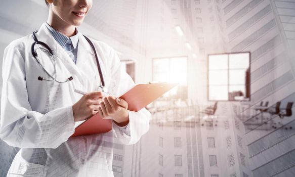Double exposure of confident female doctor in white sterile coat standing inside hospital office and modern cityscape view on background. Concept of modern medical industry