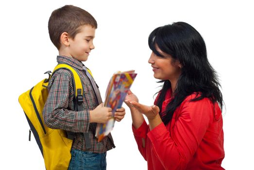 Mom giving explanation to her little son and preparing him for fist day of school,the boy holding bag and  books and looking attentive to his mother