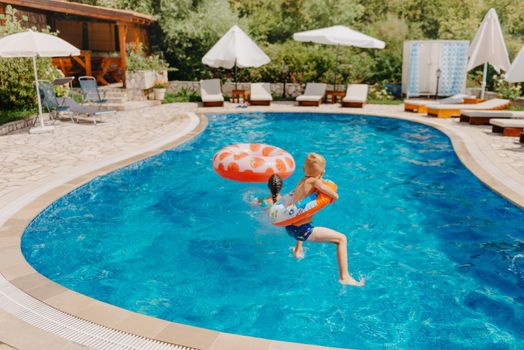 Happy child having fun on summer vacation. Kid playing with rubber duck and ball in the sea. Healthy lifestyle concept. Happy child playing in swimming pool. Summer vacations concept