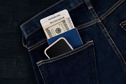 Dollars, smart, passport and plane ticket in your pocket jeans. Top view. Copy space. Still life. Flat lay
