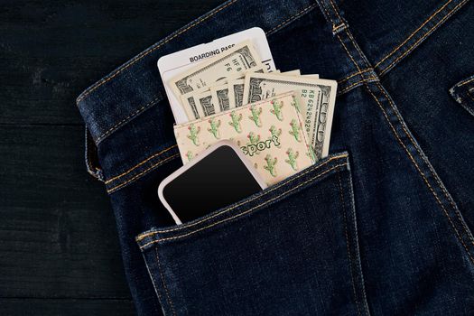 Dollars, smart and plane ticket in your pocket jeans. Top view. Copy space. Still life. Flat lay