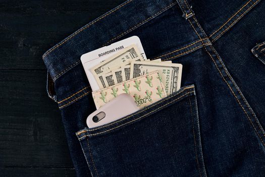 Dollars, smart and plane ticket in your pocket jeans. Top view. Copy space. Still life. Flat lay