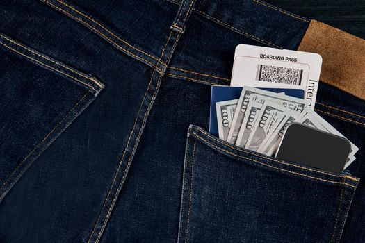 Dollars, smart, passport and plane ticket in your pocket jeans. Top view. Copy space. Still life. Flat lay