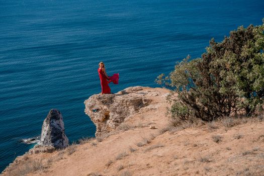 A woman in a red flying dress fluttering in the wind, against the backdrop of the sea