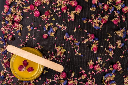 Organic honey in a small jar on a wooden background. Dried flowers. Still life. Top view. Copy space