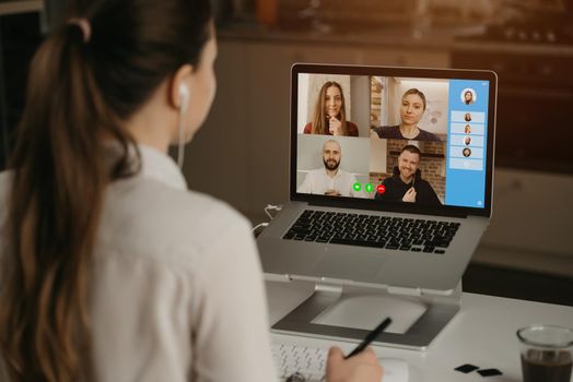 A rearview of a businesswoman at home in a video conference with her colleagues during an online meeting. Partners in a video call. Multiethnic business team having a discussion in an online meeting.
