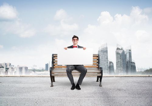 Young businessman holds a large white banner. sits on the bench