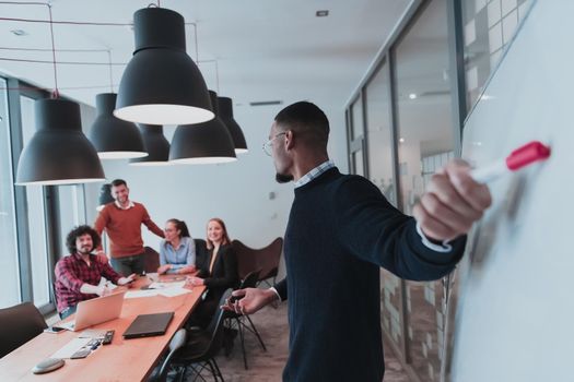 Leader give a business presentation at an office conference meeting, businessman coach mentor explains graph chart on board corporate group workshop training in the boardroom. Selective focus. High-quality photo