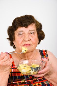 Elderly woman eating potato salad from a bowl