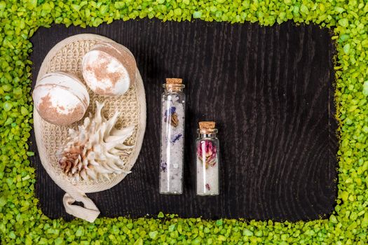 spa set - bombs for bath, sponge, sea salt in small glass jars on black wood table background. Still life. Top view. Copy space