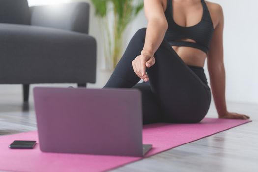 Young woman practicing yoga follow teacher in laptop online class at home. Calmness and relax concept