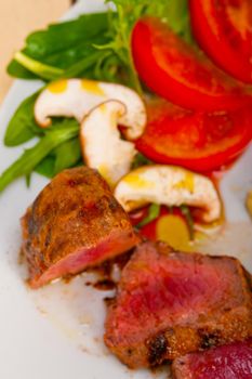 beef filet mignon grilled with fresh vegetables on side ,mushrooms tomato and arugula salad