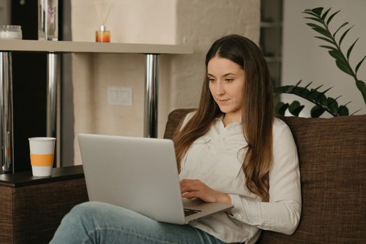 Remote work. A caucasian woman working remotely on her laptop. A businesswoman working from home on the couch.