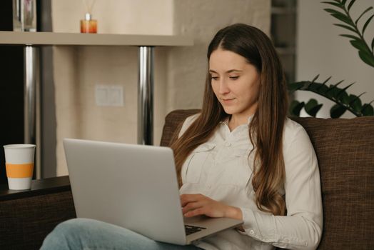 Remote work. A caucasian woman working remotely on her laptop. A businesswoman works from home sitting on the couch.