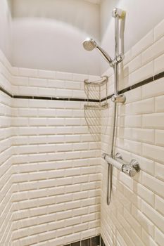 The bathroom is surrounded by brick-shaped tiles with a metal shower system