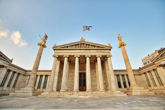 Facade of the Academy of Athens with the two columns where are the statues of the goddess Athena and the god Apollo respectively on a blue day, in Greece