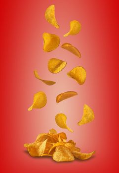 Delicious potato crisps falling down against a red background with copy space for your text or images. Crispy, palatable chips. Shadow. Advertising concept. Close-up shot.