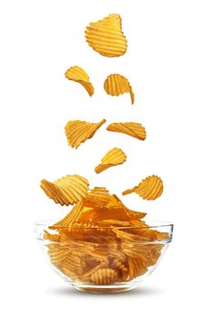 Tasty, grooved potato crisps are falling down in a glass bowl, isolated on white background with copy space for your text or images. Crispy, palatable chips. Shadow. Advertising concept. Close-up shot.