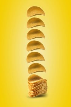 Gourmet potato crisps falling down against a yellow background with copy space for your text or images. Crispy, palatable chips. Shadow. Advertising concept. Close-up shot.